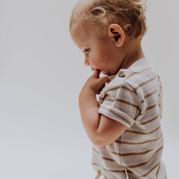 Baby wearing a striped t-shirt made of 100% organic cotton, featuring shoulder buttons for easy dressing.