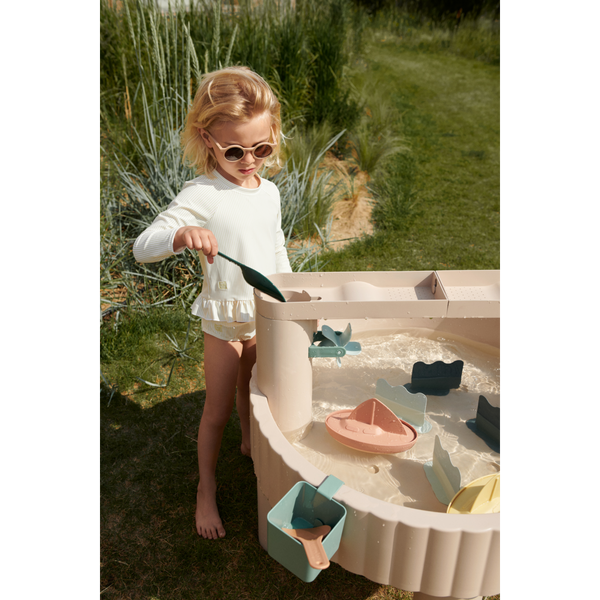 Girl playing with water and boats at the Sepp Outdoor Activity Table Sandy, promoting creativity and motor skills.