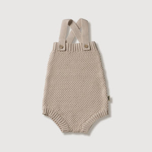 Gestrickter Baby-Strampler aus biologischer Baumwolle mit verstellbaren Trägern in neutralem Beige.