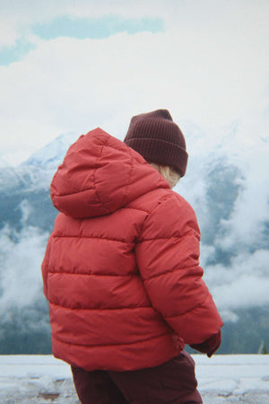 Kind trägt die Basil Wollmütze von Konges Sløjd zur roten Winterjacke