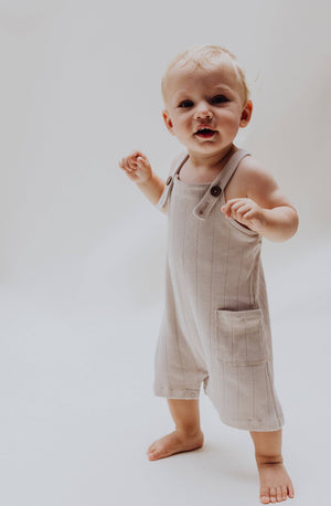 Latzhose in Rippenstrick Stone für Babys, aus Bio-Baumwolle, mit verstellbaren Trägern und Taschen.