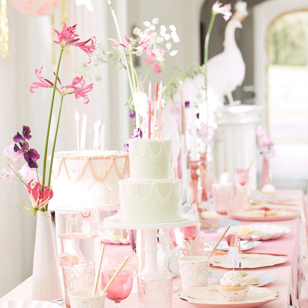 Elegant princess-themed party table with decorative cakes, floral arrangements, and pastel-colored settings for a beautiful celebration.