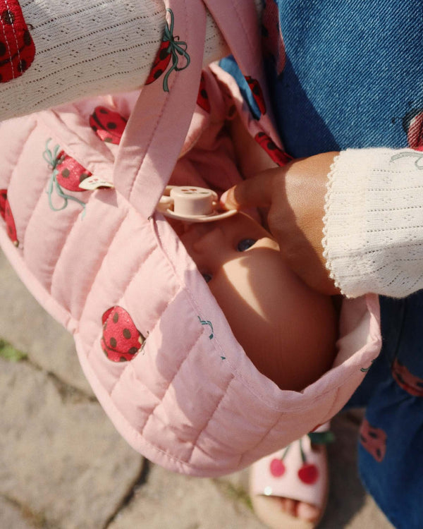 Child carrying Bonnie doll in pink ladybug-patterned basket, showcasing the exclusive gift set for young doll enthusiasts.