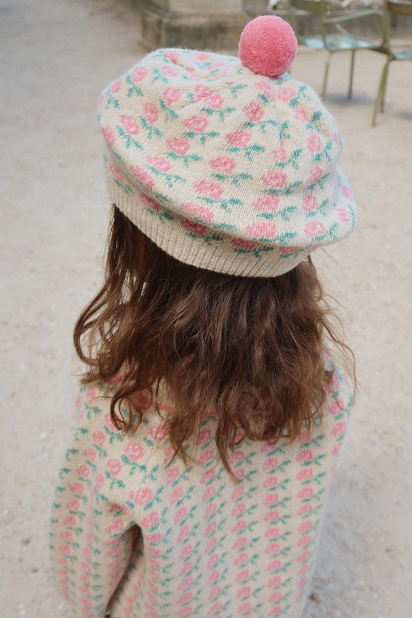 Girl wearing a floral beret with a pom-pom and cozy knit sweater, showcasing a stylish autumn look.