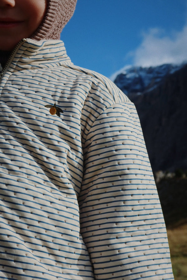 Child wearing a Thermojacke Stripe Bluie, showcasing its stylish stripes and warm design outdoors.