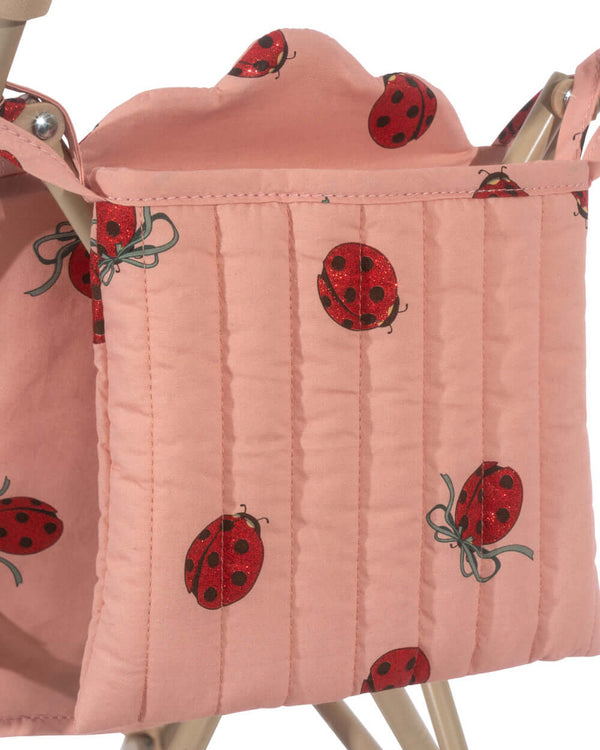 Pink ladybug-patterned fabric on the Konges Sløjd Puppenwagen Ladybug Glitter stroller, featuring practical pockets.